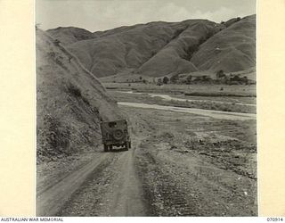 WAU - LAE ROAD, NEW GUINEA, 1944-02-26. THE ROAD 38 MILES FROM WAU LOOKING OVER SNAKE RIVER. THE ROAD AT THIS POINT IS MAINTAINED BY THE 1ST MECHANICAL EQUIPMENT PLATOON, 2/1ST RAILWAY CONSTRUCTION ..