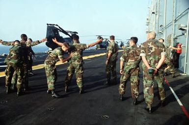 Marines of the 22nd Marine Expeditionary Unit (22nd MEU) practice body-search techniques on the flight deck of the amphibious assault ship USS SAIPAN (LHA-2) in preparation for Operation Sharp Edge. The SAIPAN is on station off the coast of Liberia