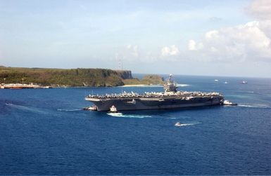 Port side view of the US Navy (USN) NIMITZ CLASS: Aircraft Carrier, USS CARL VINSON (CVN 70), being assisted by tugboats as the ship enters the harbor at Apra Harbor, Guam