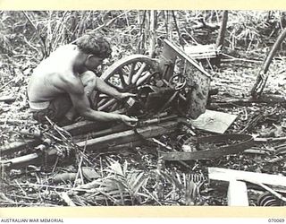 GOALING RIVER AREA, WEST NEW GUINEA. 1944-01-25. SAPPER F.J. LOWER, 2/13TH FIELD COMPANY, ROYAL AUSTRALIAN ENGINEERS EXAMINING A JAPANESE MOUNTAIN GUN THAT IS PART OF SALVAGEABLE EQUIPMENT IN ONE ..