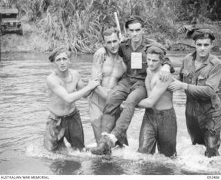 BOUGAINVILLE. 1945-05-21. TROOPS OF 58/59 INFANTRY BATTALION ASSISTING PRIVATE K.M. SPRIGG (3), WALKING WOUNDED, ACROSS THE HONGORAI RIVER AT MAYBERRY'S CROSSING. IDENTIFIED PERSONNEL ARE:- PRIVATE ..