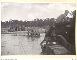 SOUTH BOUGAINVILLE. 1945-07-24. TROOPS OF 6 MECHANICAL EQUIPMENT COMPANY, ROYAL AUSTRALIAN ENGINEERS, BEING FERRIED ACROSS THE FLOODED MOBIAI RIVER ON A RAFT MADE FROM 44 GALLON DRUMS TOWED BY ..