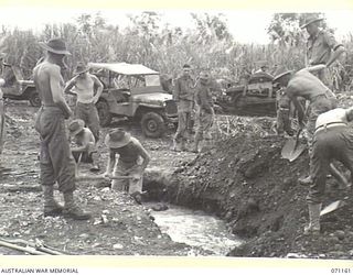 EVAPIA RIVER, NEW GUINEA, 1944-03-15. MEN OF THE 2/4TH FIELD COMPANY, ROYAL AUSTRALIAN ENGINEERS, PREPARING THE MAIN SUPPORT FOR A SUSPENSION BRIDGE CARRYING FOOT TRAFFIC AND FACILITATING DELIVERY ..