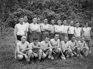 WUNUNG PLANTATION, JACQUINOT BAY, NEW BRITAIN. 1945-07-21. PRIVATE P. KYNE, FORMERLY OF COLLINGWOOD FOOTBALL CLUB (4), AND CAPTAIN OF THE SIDE, WITH MEMBERS OF THE 22 INFANTRY BATTALION TEAM WHICH ..