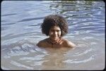 Young woman, wearing shell necklaces, bathes in shallow water