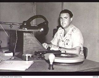 LAE, NEW GUINEA, 1945-12-21. LIEUTENANT DEAR, OFFICER COMMANDING AUSTRALIAN ARMY AMENITIES SERVICE RADIO STATION 9AB, BROADCASTING FROM ONE OF THE SMALL STUDIOS