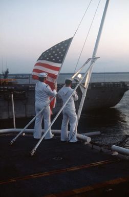 Crew members lower the national ensign during evening colors aboard the amphibious assault ship USS SAIPAN (LHA 2)