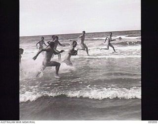 WEST WEWAK BEACH, NEW GUINEA. 1945-09-01. TROOPS OF HEADQUARTERS 6 DIVISION PLAYING FOOTBALL ALONG THE WATER'S EDGE