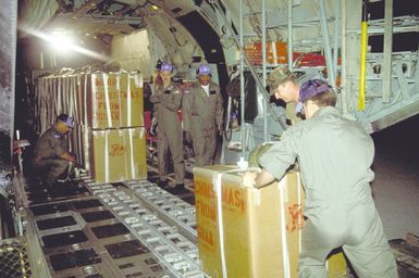 Personnel from the 345th and 21st Tactical Airlift Squadrons load Christmas packages into the hold of a C-130E Hercules aircraft. Donated gifts are being parachuted onto islands in Micronesia