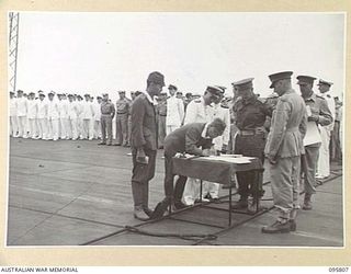 AT SEA OFF RABAUL, NEW BRITAIN. 1945-09-06. THE SURRENDER CEREMONY ON BOARD THE AIRCRAFT CARRIER HMS GLORY SHOWING GENERAL H. IMAMURA, COMMANDER EIGHTH AREA ARMY, SIGNING THE INSTRUMENT OF ..