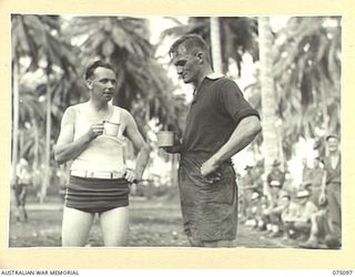 MILILAT, NEW GUINEA. 1944-08-06. TWO STAR PLAYERS IN THE SOCCER MATCH BETWEEN TEAMS FROM HEADQUARTERS, 5TH DIVISION AND THE 4TH INFANTRY BRIGADE ENJOY A DRINK AT HALF TIME DURING THEIR GAME ON THE ..