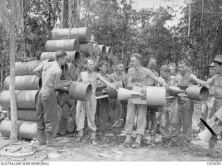 NADZAB, NEW GUINEA. C. 1944-02. BARE TO THE WAIST, ARMOURERS OF NO. 24 (VULTEE VENGEANCE) SQUADRON RAAF PASSING TAILS FOR 500LB BOMBS PRIOR TO ATTACHING THEM TO BOMBS FOR LOADING THEM ONTO AIRCRAFT