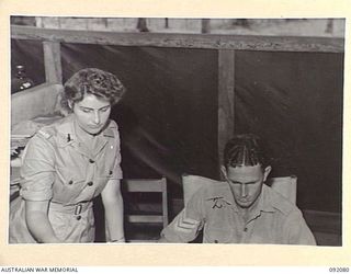 LAE, NEW GUINEA, 1945-05-21. PRIVATE J.D. REEVES, AUSTRALIAN WOMEN'S ARMY SERVICE (1), AND SERGEANT W. FITZPATRICK (2), CHECKING DETAILS FOR AN ISLAND SHIPMENT AT THE AUSTRALIAN ARMY CANTEENS ..