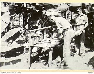 NEW GUINEA, 1942-08-03. THE COOKHOUSE OF ONE SMALL BAND OF AUSTRALIAN TROOPS IN NEW GUINEA IS SET IN THE MIDST OF THE DENSE FOLIAGE OF A BANANA PLANTATION