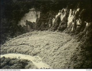 NORTH EAST NEW GUINEA. 1945-03-09. NOT ONLY DO AIRMEN AND GROUND FORCES HAVE TO CONTEND WITH THIS TYPE OF RUGGED JUNGLE COUNTRY BUT THEY ALSO HAVE TO FACE SHEER ROCK-FACED CLIFFS LIKE THOSE SHOWN ..