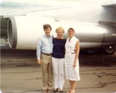 Three people posing in front of a plane