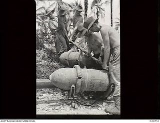 MOMOTE, LOS NEGROS ISLAND, ADMIRALTY ISLANDS. 1944-03-08. RAAF ARMOURERS MANHANDLING BOMBS BEFORE A RAID BY RAAF KITTYHAWK FIGHTER-BOMBER AIRCRAFT FROM MOMOTE AIRSTRIP IN THE ADMIRALTY ISLANDS