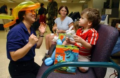 Cheryl Cheryltaiva entertains Tifany Anderson's son, Hunter Anderson at the Air Mobility Command (AMC) terminal, on Hickam Air Force Base (AFB), Hawaii, after being airlifted from typhoon damaged Guam