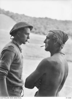 OWEN STANLEY RANGES, NEW GUINEA. C. 1942-09-01. AUSTRALIAN PRIVATES E.L. FLOWER AND E.O. MOREY HAVE A CIGARETTE DURING A BREAK IN THE JUNGLE FIGHTING AGAINST THE JAPANESE IN THE KOKODA AREA. MOREY ..