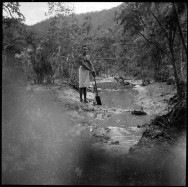 Man with a shovel beside pools of water in Chinnery's garden, Malaguna Road, Rabaul, New Guinea, 1937 / Sarah Chinnery