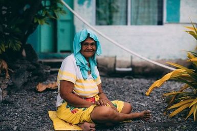 Woman sitting on gravel, Fakaofo, Tokelau