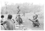 Group gathered around pieces of pig ready for distribution