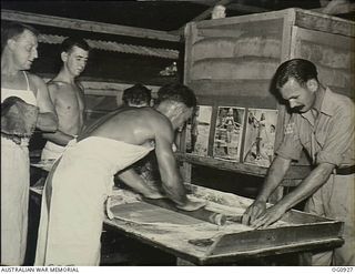 NADZAB, NEW GUINEA. C. 1944-02. COOKS WITH NO. 24 SQUADRON RAAF PREPARE PASTRY ON TABLES IN FRONT OF BREAD STORAGE BINS FEATURING "PIN-UPS" OF TIVOLI GIRL PERFORMERS FROM THE TIVOLI THEATRE. LEFT ..