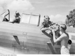 TOROKINA, BOUGAINVILLE ISLAND, SOLOMON ISLANDS. 1945-04-11. 73654 LEADING AIRCRAFTMAN L. R. BARTHOLOMEW OF SYDNEY, NSW, HANDS AN OBLIQUE CAMERA TO 434378 FLYING 0FFICER (FO) BILL TUCKER OF ..