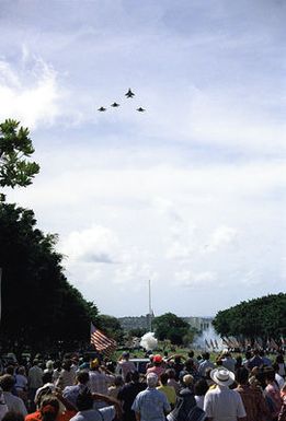 A saluting gun is fired as a flight of F-15 Eagle aircraft passes over the National Memorial Cemetery of the Pacific, also known as the Punchbowl, during the cemetery's Memorial Day observances.