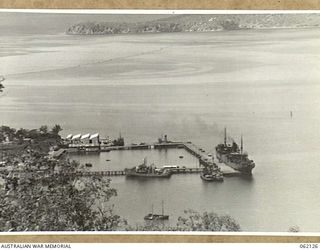 PORT MORESBY, NEW GUINEA. 1943-12-29. LOOKING DOWN ON SHIPPING IN THE DOCKS, SHOWING THE ANTI-SUBMARINE BOOM STRETCHING ACROSS THE HARBOUR ENTRANCE