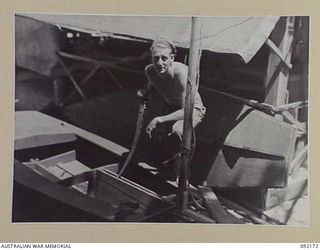 JACQUINOT BAY, NEW BRITAIN. 1945-05-18. CORPORAL P. BECKER, PUBLIC RELATIONS, HEADQUARTERS 5 DIVISION, PUTTING THE FINISHING TOUCHES TO A HOME-MADE SAILING BOAT WHICH PROVED TO BE THE FASTEST BOAT ..
