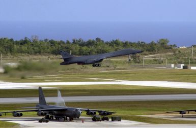 Near several parked US Air Force (USAF) B-52 Stratofortress bombers, a B-1B Lancer Bomber, deployed from Dyess Air Force Base (AFB), Texas, takes off from Andersen AFB, Guam, in support of the 7th Air Expeditionary Wing's mission