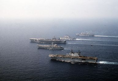 Ships from four nations sail in formation during the NATO Southern Region exercise DRAGON HAMMER '90. The ships are, from front: amphibious assault ship USS SAIPAN (LHA 2), the Spanish aircraft carrier SPS PRINCIPE DE ASTURIAS (R-11), the nuclear-powered aircraft carrier USS DWIGHT D. EISENHOWER (CVN 69), the Italian light aircraft carrier ITS GIUSEPPE GARIBALDI (C-551), and the British light aircraft carrier HMS INVINCIBLE (R-05)