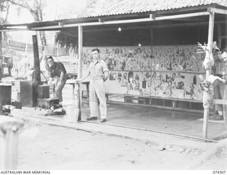 LAE, NEW GUINEA. 1944-07-05. CORPORAL G. RYAN (1) AND PRIVATE S. FURNESS (2) COOKS OF "G" MESS, HEADQUARTERS, NEW GUINEA FORCE AND THEIR "PIN- UP" GIRLS WHICH DECORATE THE WALLS OF THE KITCHEN