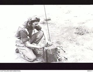 RABAUL, NEW BRITAIN, 1945-12-06. A SIGNALLER DEMONSTRATING WITH A KEY ON A WIRELESS SET 108 DURING A DEMONSTRATION OF VARIOUS INFANTRY WEAPONS AND EQUIPMENT