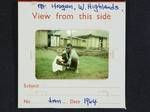 [Portrait of man and child with traditional house in background, woman standing in doorway], Mt Hagen, Western Highlands, Jan 1964