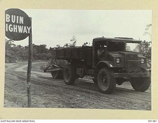 BOUGAINVILLE. 1945-04-30. A TRUCK TOWING A ROLLER DURING THE CONSTRUCTION OF A 3 TONNER ROAD BY ENGINEERS OF 15 FIELD COMPANY, ROYAL AUSTRALIAN ENGINEERS. THE BUIN ROAD SIGN IN THE FOREGROUND IS ..