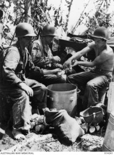 1943-01-27. PAPUA. SANANANDA AREA. AFTER HAVING BEEN IN ACTION DURING WHICH TIME THEIR ONLY FOOD WAS BULLY BEEF AND BISCUITS, THESE AMERICANS PREPARE A HOT MEAL - JUNGLE STEW