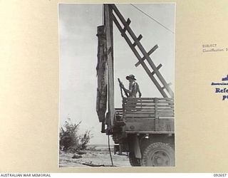 MINGA CREEK, WEWAK AREA, NEW GUINEA. 1945-05-30. MEMBERS OF 9 PLATOON, 2/8 FIELD COMPANY ROYAL AUSTRALIAN ENGINEERS, HOISTING A HEAVY PILE UP ON A PILE DRIVER WHICH IS MOUNTED ON A 3-TON TRUCK AT ..