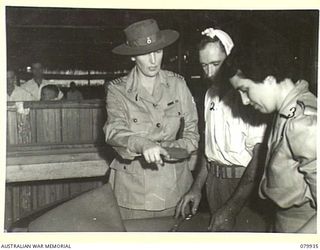 LAE, NEW GUINEA. 1945-03-27. LADY WAKEHURST (1), INSPECTING THE HAD CRAFTS SECTION OF THE RED CROSS RECREATION HUT. IDENTIFIED PERSONNEL ARE:- NX120959 CORPORAL C. HEATHERFIELD (2), RED CROSS FIELD ..