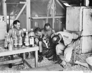 Madang, New Guinea, 1945-08-15. Four RAAF officers serving with Headquarters, RAAF Northern Command (NORCOM), celebrate Victory in the Pacific (VP) Day with a session of solid drinking. The men are ..