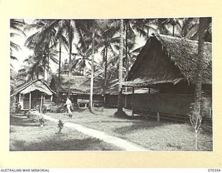 MILNE BAY, NEW GUINEA, 1944-02-10. THE COMMANDER'S HUT IS PICTURED ON THE LEFT WITH PART OF THE ADMINISTRATION HUTS AT HEADQUARTERS, MILNE BAY BASE SUB AREA. THE NEAR WING OF THIS BLOCK STANDS ON ..