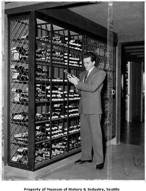 Rudy Valiani inspecting wine in wine cellar at Canlis, Seattle, March 28, 1958