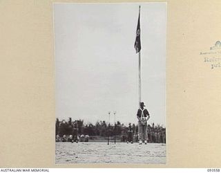 WUNUNG PLANTATION, JACQUINOT BAY, NEW BRITAIN. 1945-07-01. THE ROYAL STANDARD FLYING FROM THE MASTHEAD AT THE INSPECTION PARADE BY HIS ROYAL HIGHNESS, THE DUKE OF GLOUCESTER, GOVERNOR-GENERAL OF ..