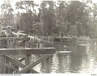 JACQUINOT BAY, NEW BRITAIN. 1945-02-09. A NEW HIGH LEVEL BRIDGE BEING BUILT OVER THE KALUMALAGI RIVER BY TROOPS OF THE 13TH FIELD COMPANY. ON THE RIGHT CAN BE SEEN THE BARGE SLIPWAY WHICH IS ALSO ..