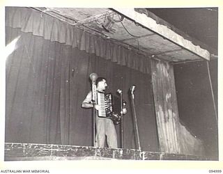 JACQUINOT BAY. 1945-08-17. STAFF SERGEANT L. CAMPERA, HEADQUARTERS AUSTRALIAN ARMY AMENITIES SERVICE, ENTERTAINING THE HUGE CROWD AT THE CONCERT, BEFORE THE ARRIVAL OF GRACIE FIELDS