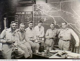 Madang, New Guinea, 1945-07-20. The night shift staff in the Operations Room at Headquarters, RAAF Northern Command (NORCOM), enjoy a supper of sandwiches and mugs of tea. The men are (left to ..