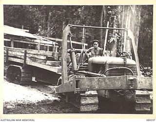 CAPE CUNNINGHAM, NEW BRITAIN, 1944-12-16. SAPPER G W HUTCHINSON, 2/2 FORESTRY COY, (1), DRIVING A TRACTOR AND A TRAILER OF SAWN TIMBER TO A WAITING BARGE