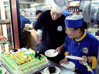 Onboard the US Navy (USN) Emory S. Land Class Submarine Tender, USS FRANK CABLE (AS 40), USN Culinary SPECIALIST Third Class (CS3) Rebecca Brucker, and Machinist's Mate Fireman (MMFN) Scott Miller, cut a cake commemorating the submarine tenders 10th Anniversary of being forward deployed to Guam