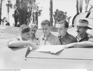 PIVA AIRFIELD, TOROKINA, BOUGAINVILLE ISLAND, SOLOMON ISLANDS. C. 1945-01-16. SENIOR OFFICERS OF RAAF, AIF AND ROYAL NEW ZEALAND AIR FORCE PLANNING A MISSION TO BOMB JAPANESE TROOPS ON BOUGAINVILLE ..